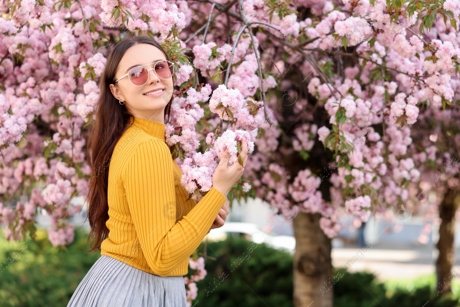 Photo of Beautiful woman in sunglasses near blossoming tree on spring day