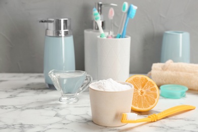 Bowl with baking soda and toothbrush on marble table