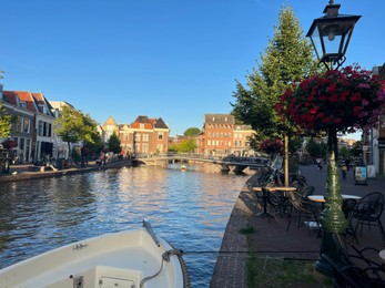 Leiden, Netherlands - August 1, 2022: Picturesque view of city canal with bridge, outdoor cafe and beautiful buildings