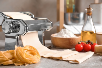 Pasta maker with dough and products on kitchen table