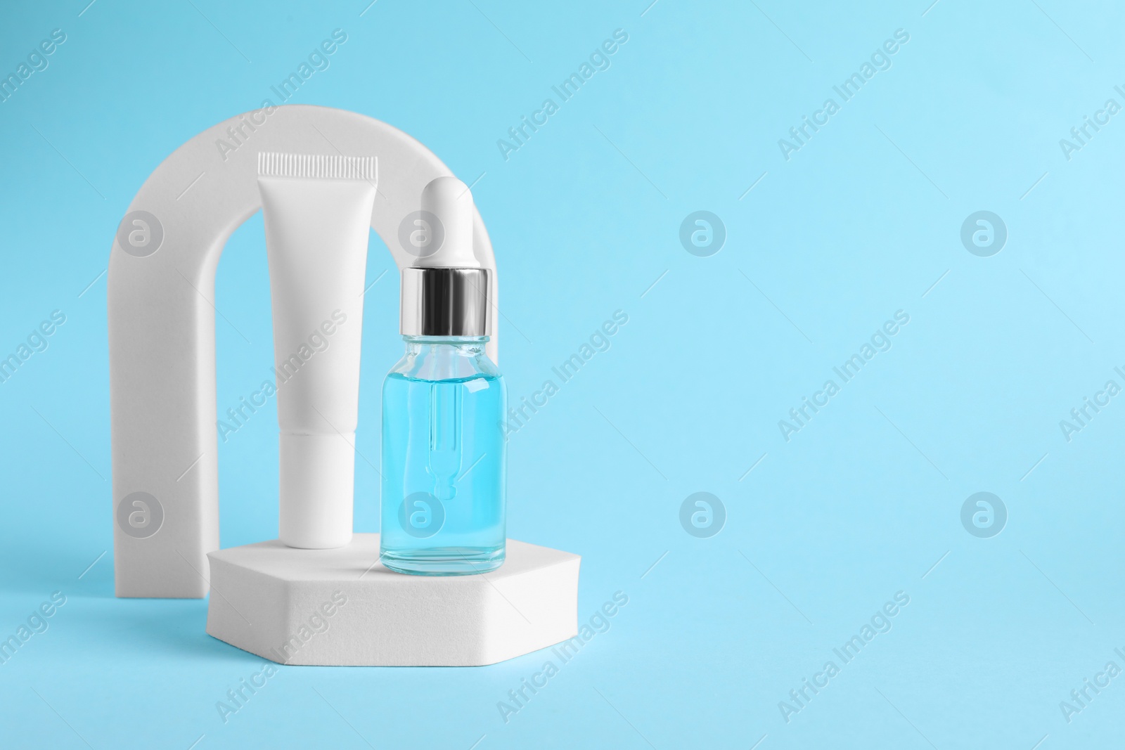 Photo of Stylish presentation of cosmetic serum on light blue background, space for text