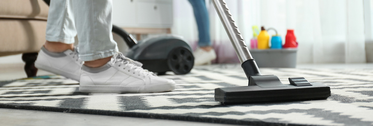 Image of Cleaning service worker vacuuming carpet indoors, closeup. Banner design