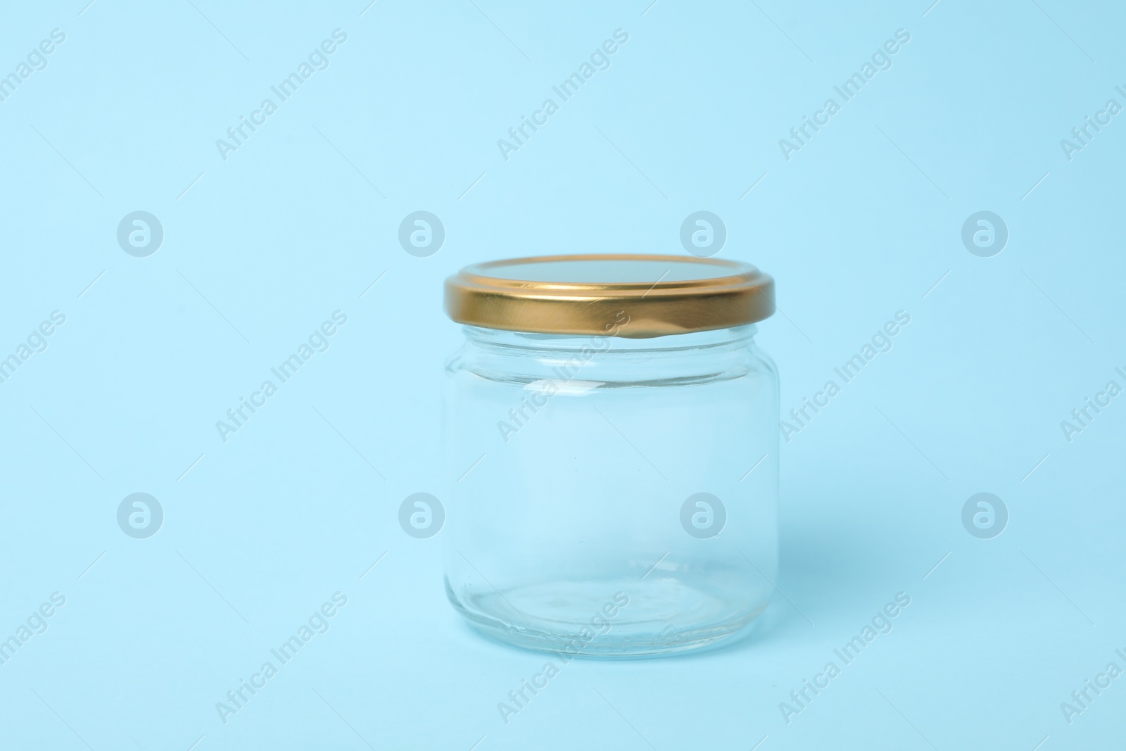 Photo of Closed empty glass jar on light blue background