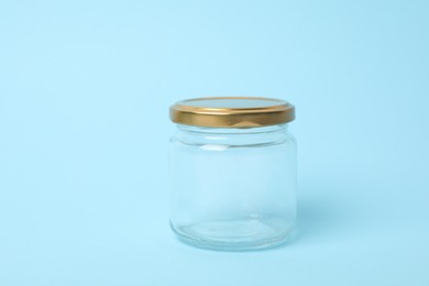Photo of Closed empty glass jar on light blue background