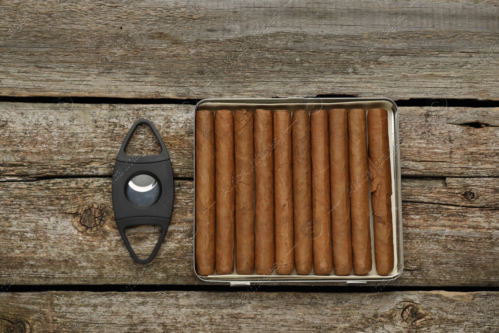 Photo of Cigars and guillotine cutter on wooden table, flat lay