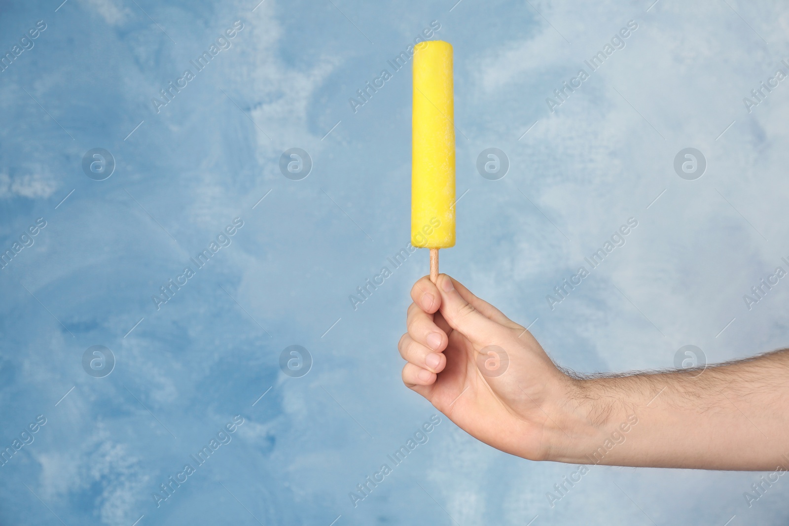 Photo of Man holding yummy ice cream on color background. Focus on hand