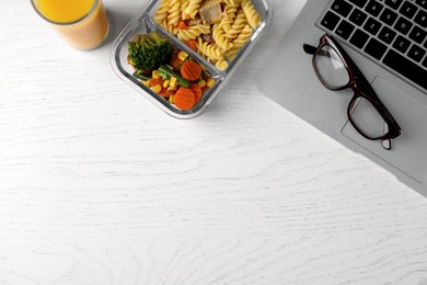 Container of tasty food, laptop and glasses on white wooden table, flat lay with space for text. Business lunch