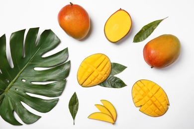 Photo of Fresh mango and green leaves on white background, flat lay