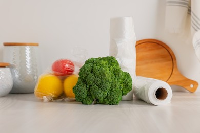 Photo of Rolls of plastic bags and fresh products on white table