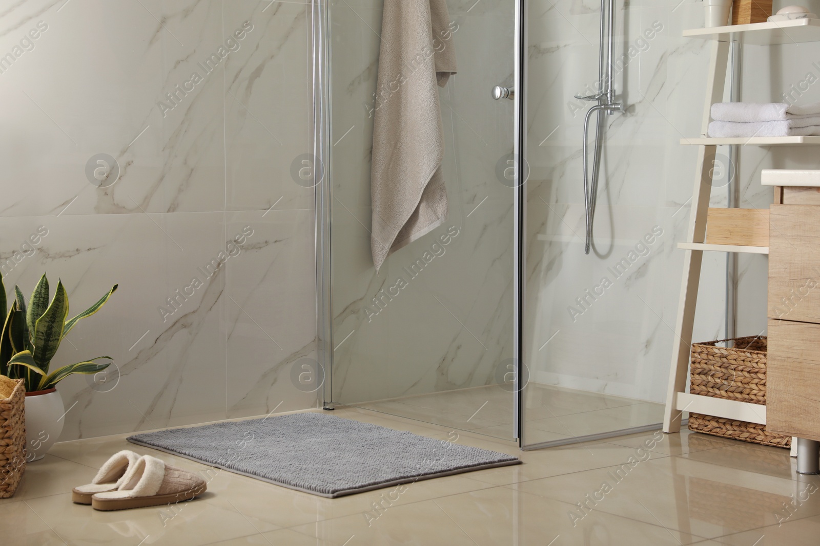 Photo of Soft grey bath mat and slippers on floor in bathroom