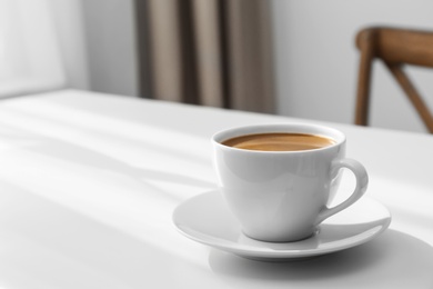 Photo of Cup of hot aromatic coffee on white table indoors. Space for text