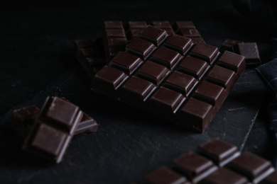 Photo of Tasty dark chocolate bars on black table