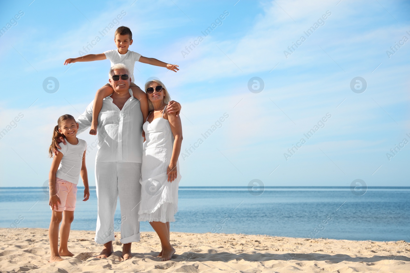 Photo of Cute little children with grandparents spending time together on sea beach