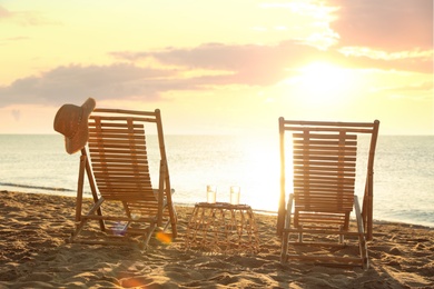 Wooden deck chairs and drinks near sea at sunset. Summer vacation