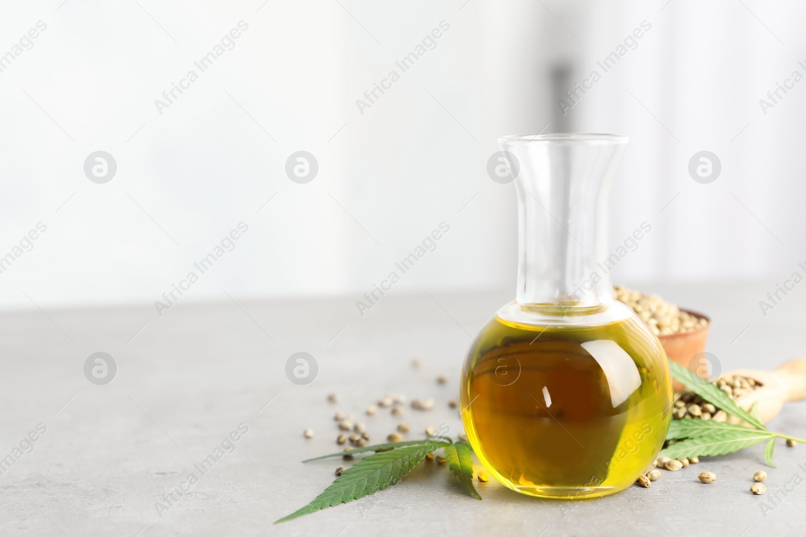 Photo of Bottle with hemp oil, leaf and seeds on table. Space for text