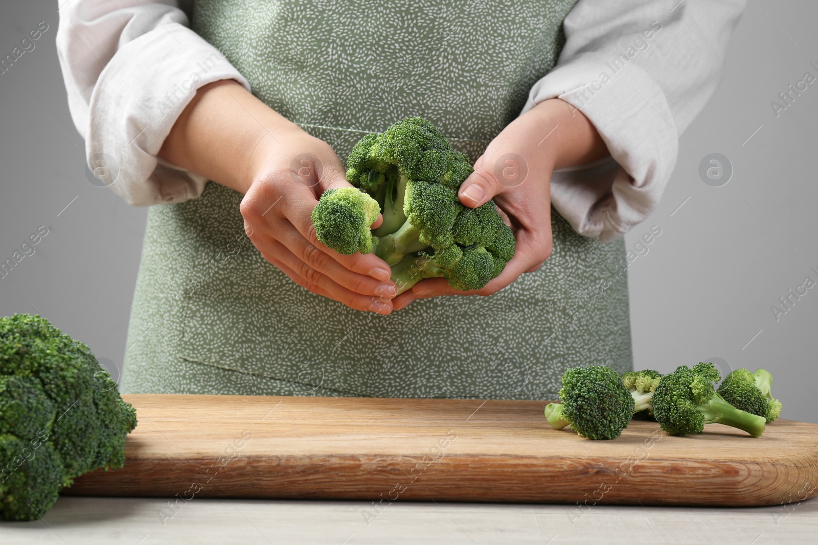 Photo of Woman with fresh broccoli at wooden table, closeup