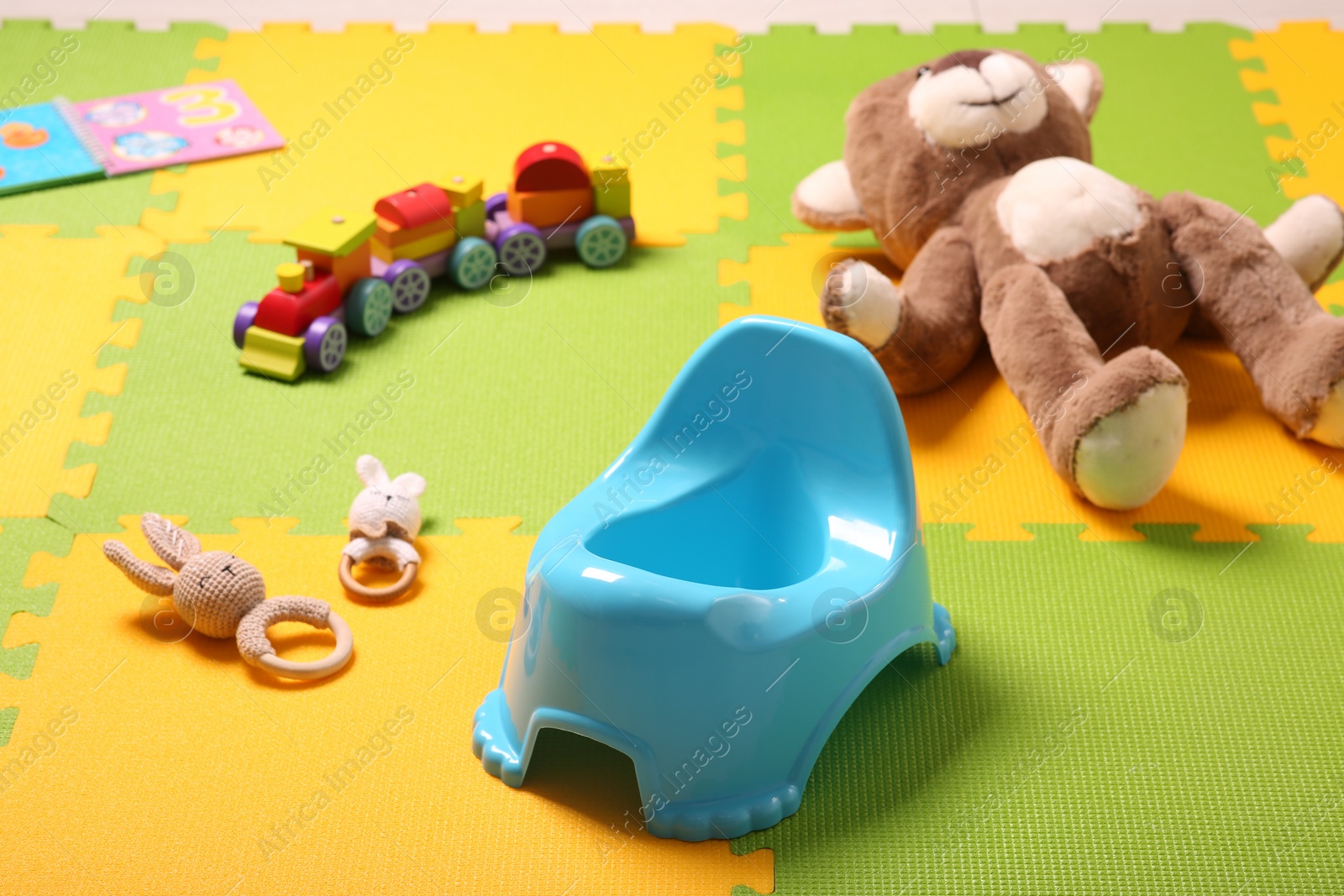 Photo of Light blue baby potty and toys on colorful puzzle mat. Toilet training