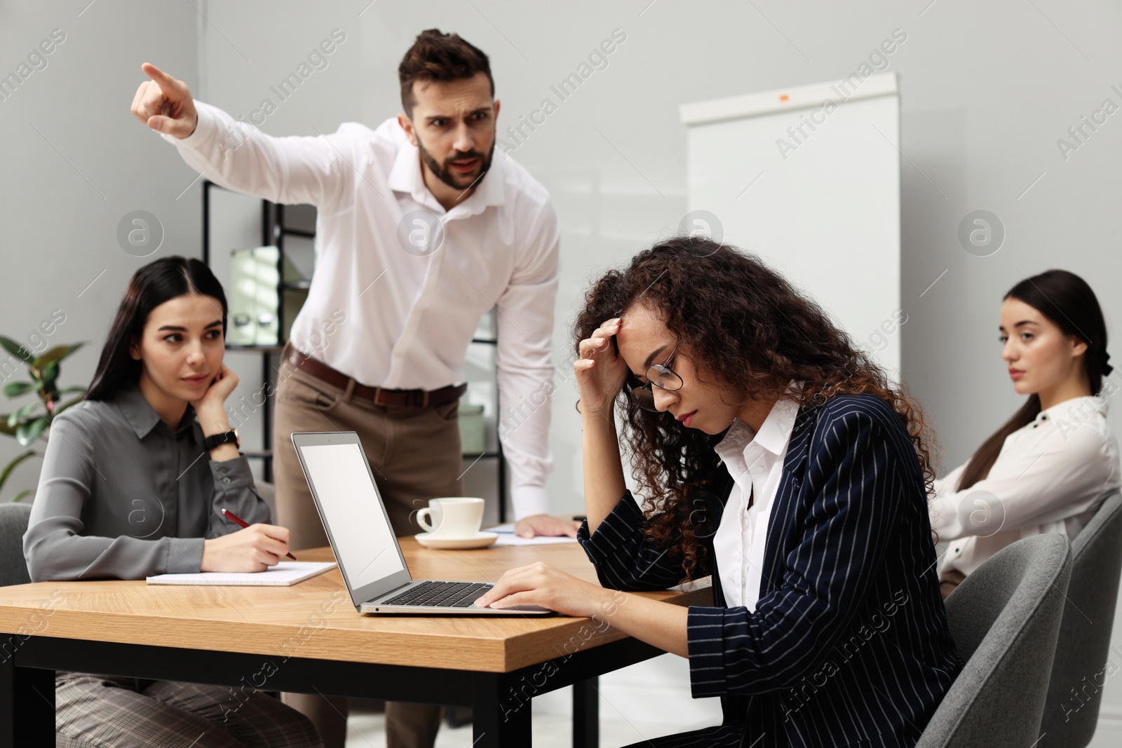Photo of Man screaming at African American woman in office. Racism concept