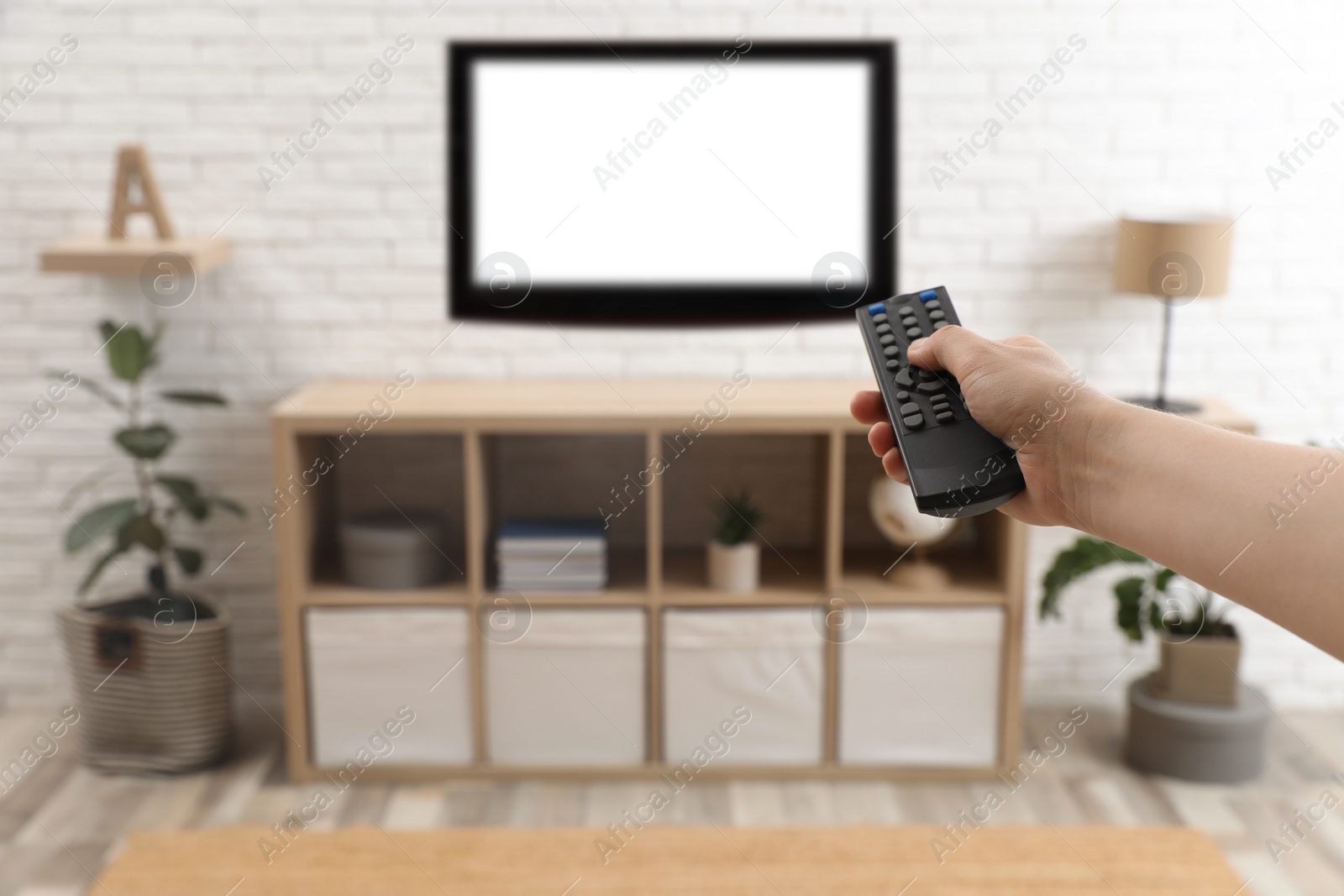 Photo of Young man switching channels on TV set with remote control at home, closeup