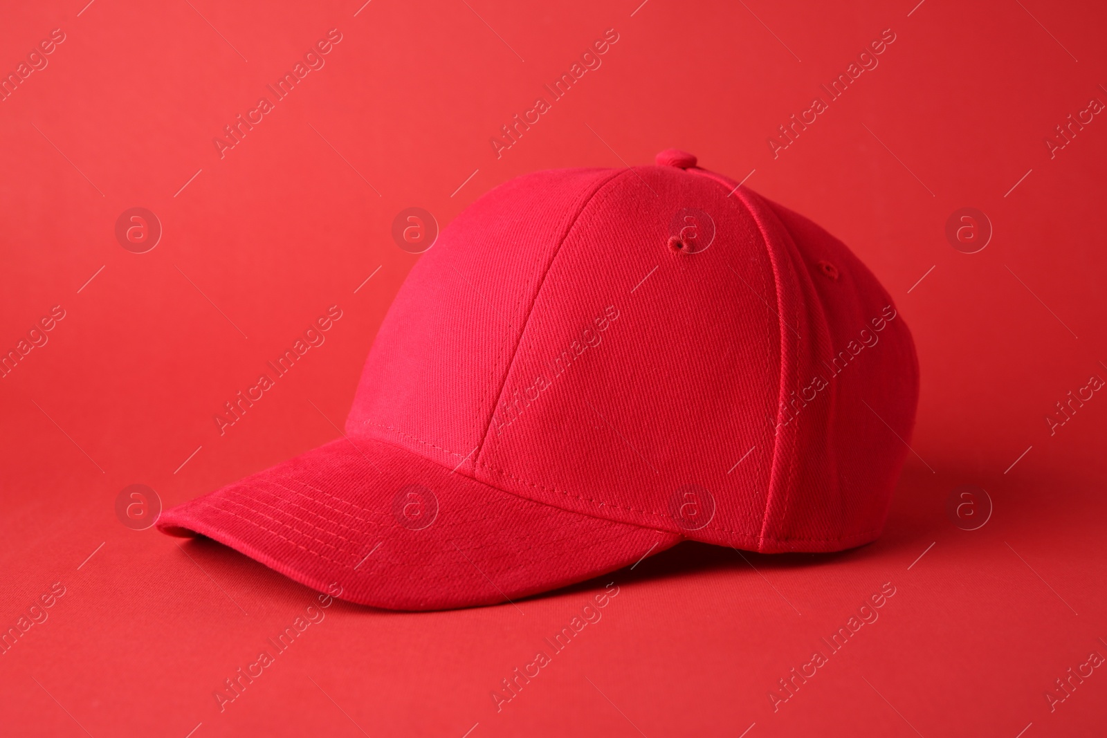 Photo of Stylish red baseball cap on color background