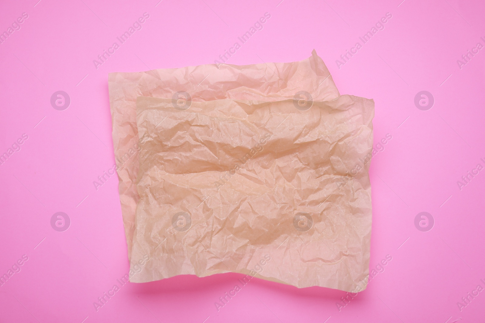 Photo of Sheets of crumpled baking paper on pink background, top view