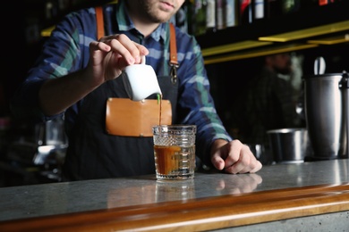 Barman making White Russian cocktail at counter in pub, closeup. Space for text
