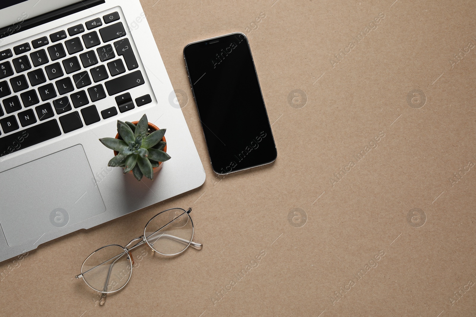 Photo of Modern laptop, houseplant, glasses and smartphone on beige table, flat lay. Space for text