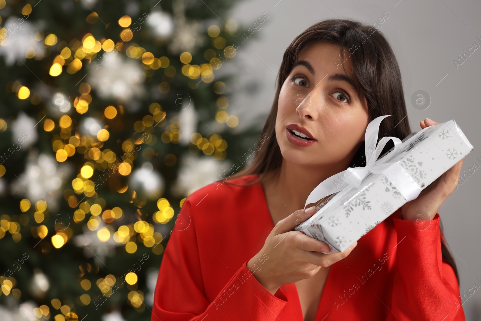 Photo of Surprised woman with Christmas gift indoors. Space for text