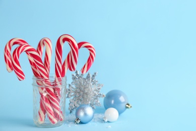 Photo of Candy canes and Christmas decor on light blue background, space for text