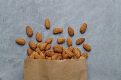 Photo of Paper bag with delicious almonds on grey table, top view