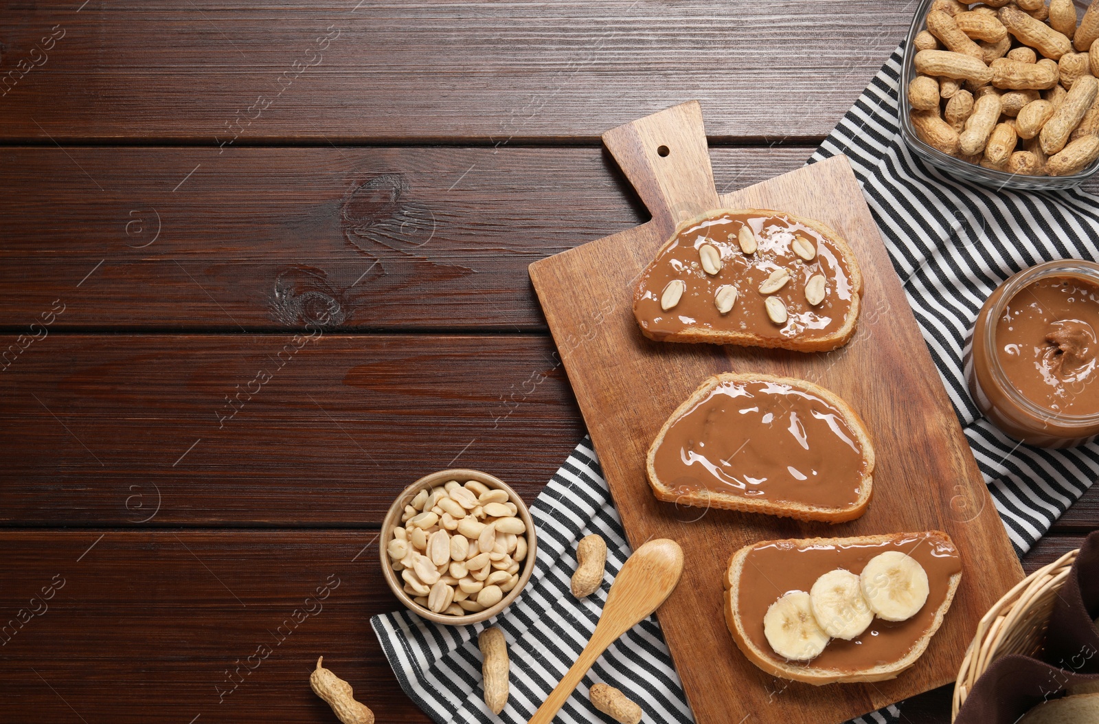 Photo of Toasts with tasty nut butter, banana slices and peanuts on wooden table, flat lay. Space for text