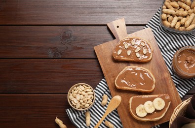 Photo of Toasts with tasty nut butter, banana slices and peanuts on wooden table, flat lay. Space for text