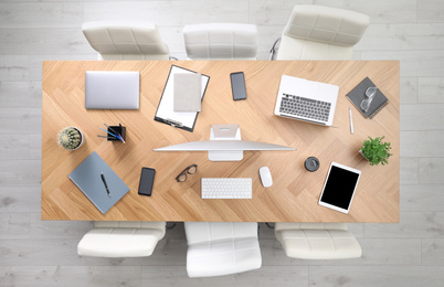 Photo of Modern office table with devices and chairs, top view