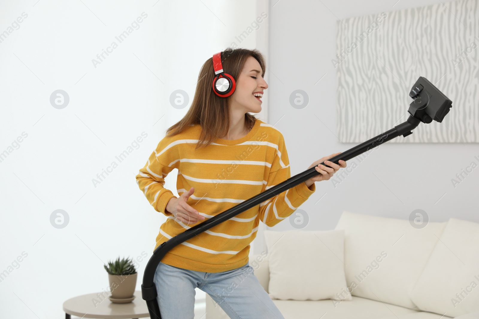 Photo of Young woman having fun while vacuuming at home