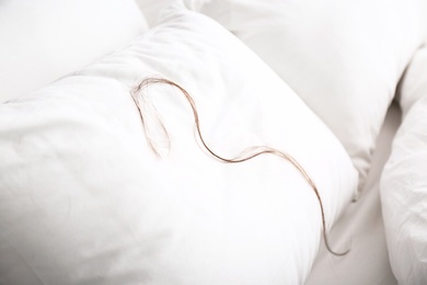 Photo of White pillow with fallen long hair on bed