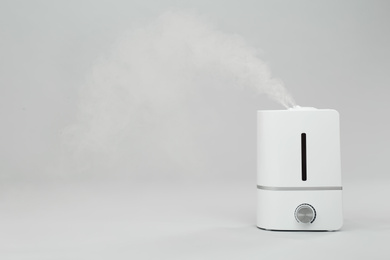 Photo of Modern air humidifier on light grey background. Space for text