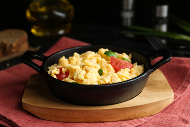 Tasty scrambled eggs with sprouts and cherry tomato in frying pan on table