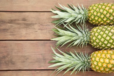 Photo of Delicious ripe pineapples on wooden table, flat lay. Space for text