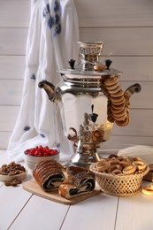 Photo of Traditional Russian samovar and treats on white wooden table