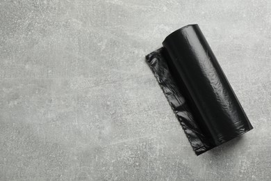 Photo of Roll of black garbage bags on grey stone table, top view. Space for text