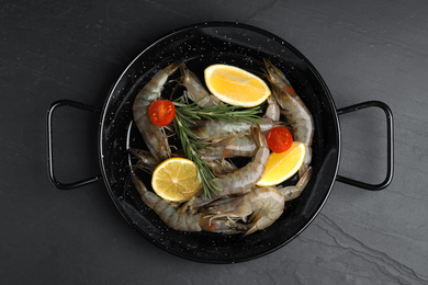 Photo of Fresh raw shrimps with lemon slices on black table, top view