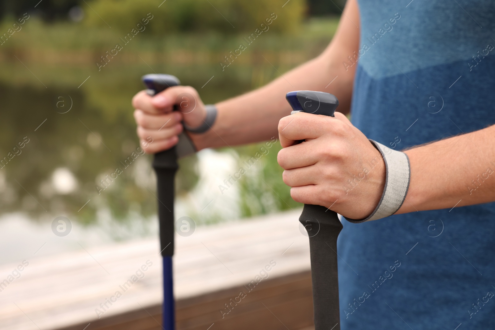 Photo of Man practicing Nordic walking with poles outdoors, closeup