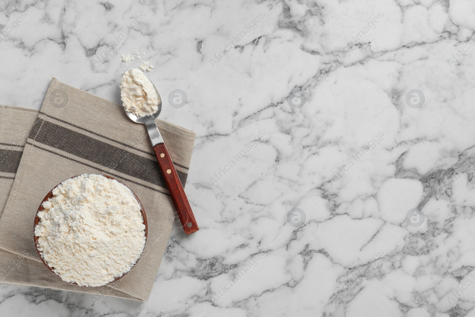 Photo of Bowl and spoon with flour on light background, top view