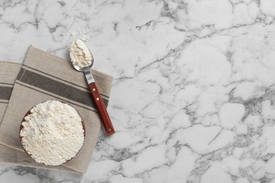 Photo of Bowl and spoon with flour on light background, top view