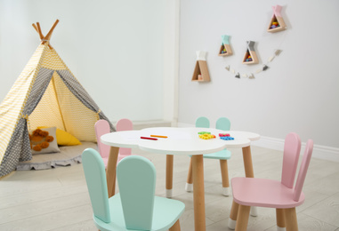 Photo of Cute children's room interior with teepee tent and little table