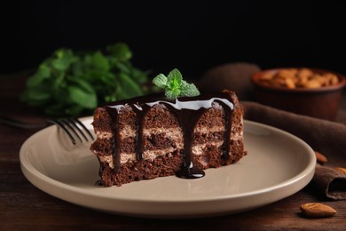 Photo of Piece of tasty homemade chocolate cake with mint on wooden table, closeup
