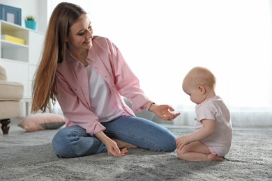 Photo of Happy mother with little baby on floor indoors