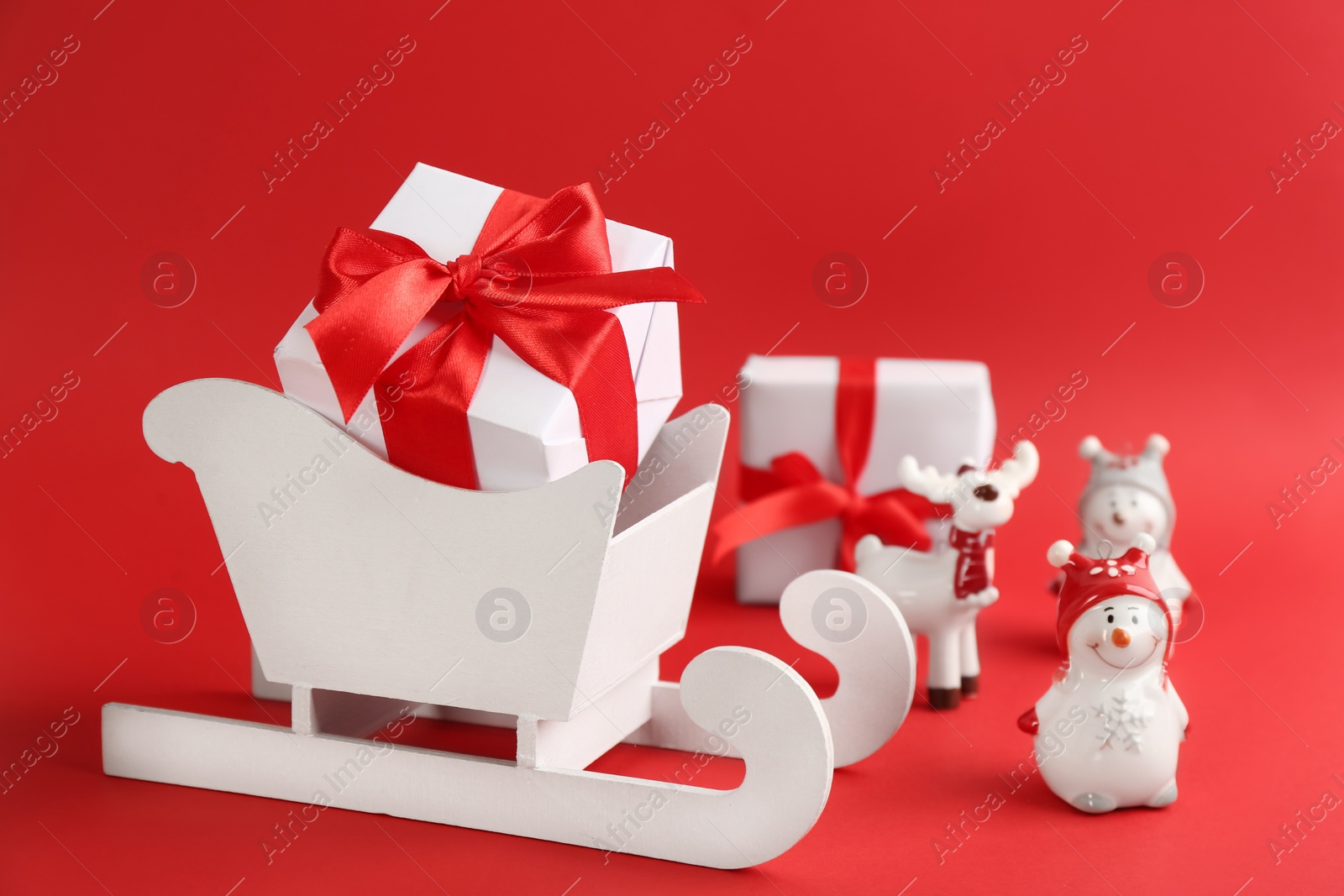 Photo of Beautiful Christmas composition with miniature sleigh on red background