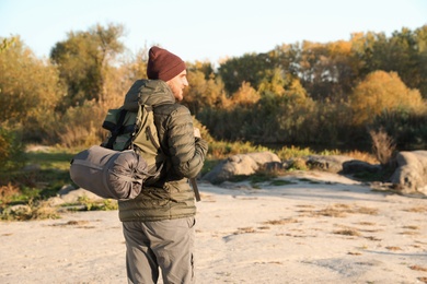 Male camper with backpack and sleeping bag in wilderness. Space for text