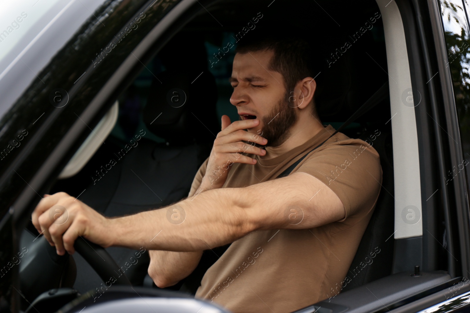Photo of Tired man yawning while driving his modern car